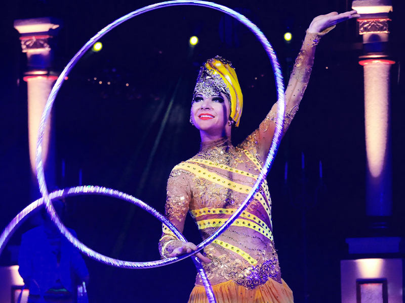 Smiling girl spins two hoops in one hand. The Nutcracker by Moscow circus on ice